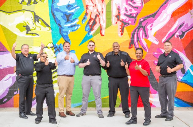 Employees giving the thumbs up in front of colorful wall