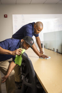 2 commercial cleaners wiping down a desk and chair