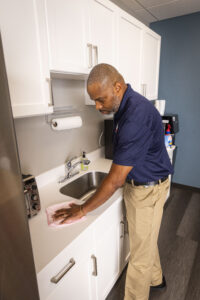 janitor cleaning high touch surface in shared office kitchenette