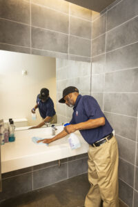 Janitorial worker wiping down sink in bathroom