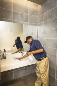 Janitorial day porter wiping sink in restroom
