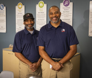 2 janitorial employees posed professionally in uniform, smiling at camera